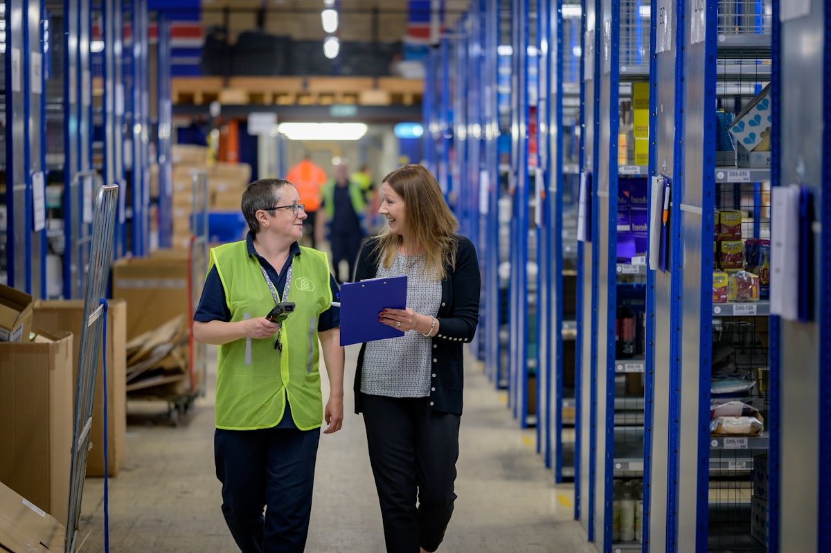 Warehouse staff walking between storage racks